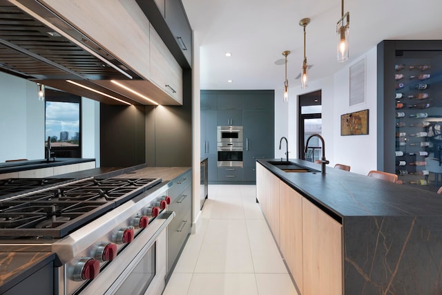 kitchen with stainless steel appliances, pendant lighting, light brown cabinets, sink, and an island with sink