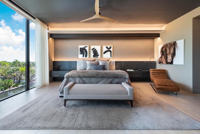 bedroom featuring expansive windows, hardwood / wood-style flooring, ceiling fan, and access to outside