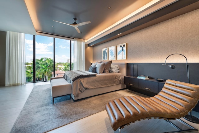 bedroom with expansive windows, access to exterior, light wood-type flooring, and ceiling fan