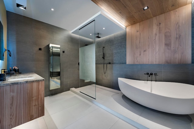 bathroom featuring tile patterned flooring, vanity, shower with separate bathtub, and tile walls