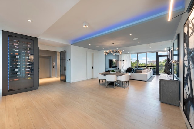 living room with light wood-type flooring, an inviting chandelier, and expansive windows