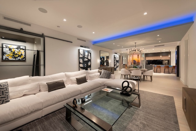 living room featuring hardwood / wood-style flooring, a barn door, and an inviting chandelier