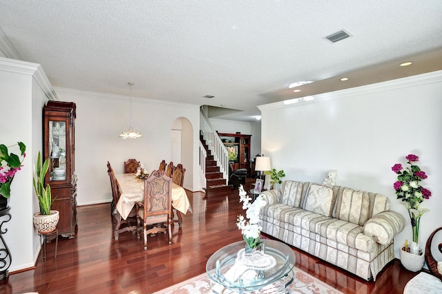 living room with a textured ceiling, crown molding, dark wood-type flooring, and a notable chandelier