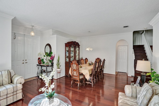 living room featuring a textured ceiling, ornamental molding, and dark wood-type flooring