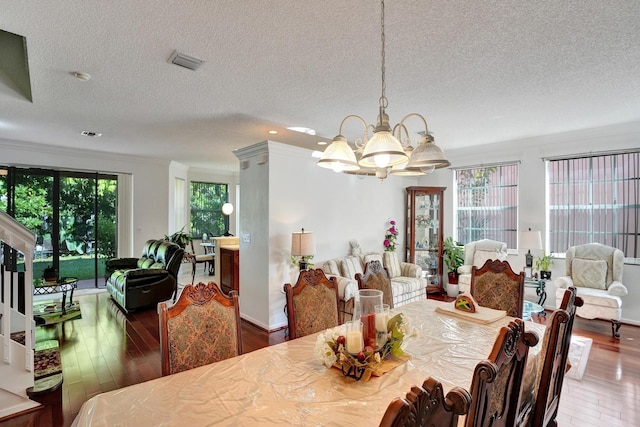 dining area featuring an inviting chandelier, a textured ceiling, crown molding, and hardwood / wood-style floors