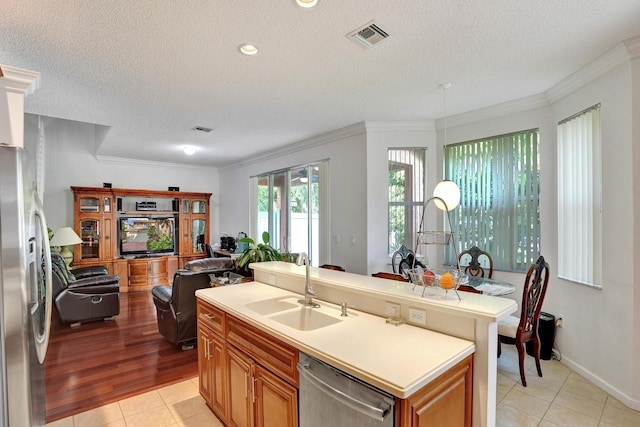 kitchen with an island with sink, stainless steel appliances, light hardwood / wood-style floors, and a textured ceiling