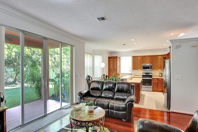 living room featuring ornamental molding, light hardwood / wood-style floors, and a textured ceiling