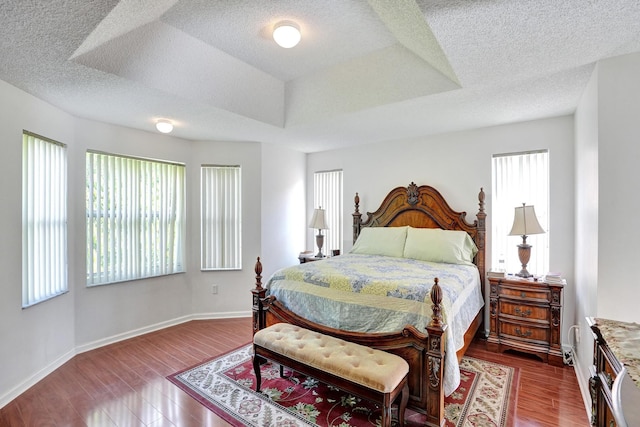 bedroom featuring wood-type flooring, a textured ceiling, and a raised ceiling