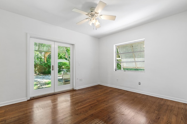 spare room with a ceiling fan, dark wood-style flooring, baseboards, and a healthy amount of sunlight