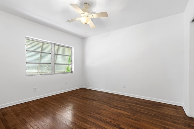 spare room with dark wood-style flooring, a ceiling fan, and baseboards