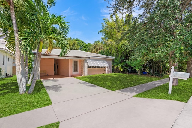 single story home featuring driveway, a front yard, an attached carport, and stucco siding