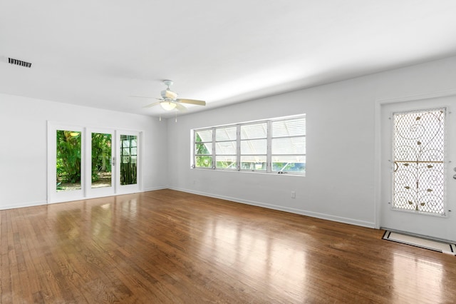 interior space with visible vents, ceiling fan, wood finished floors, and baseboards