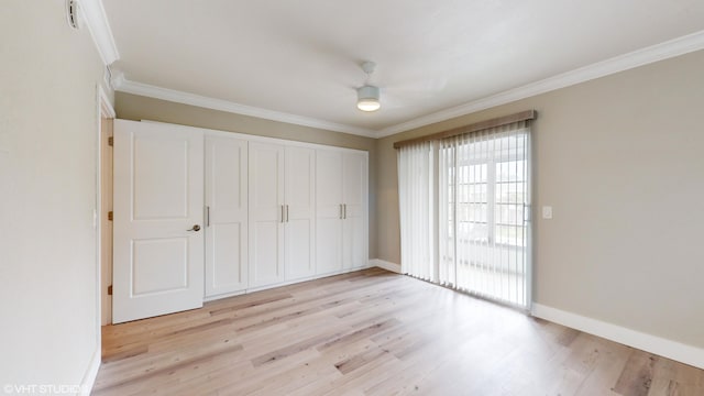 unfurnished bedroom featuring light wood-type flooring, a closet, and crown molding