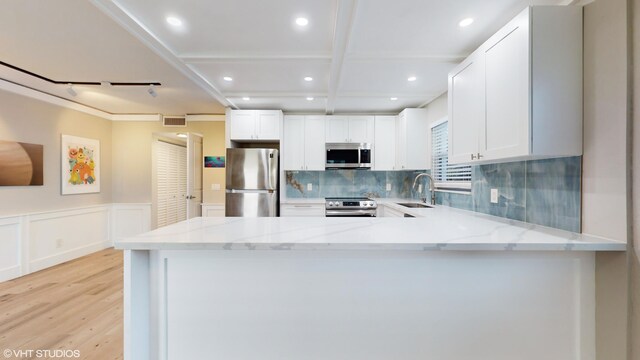 kitchen with light hardwood / wood-style flooring, white cabinets, tasteful backsplash, and sink