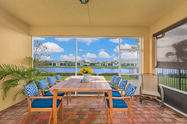 sunroom featuring a water view