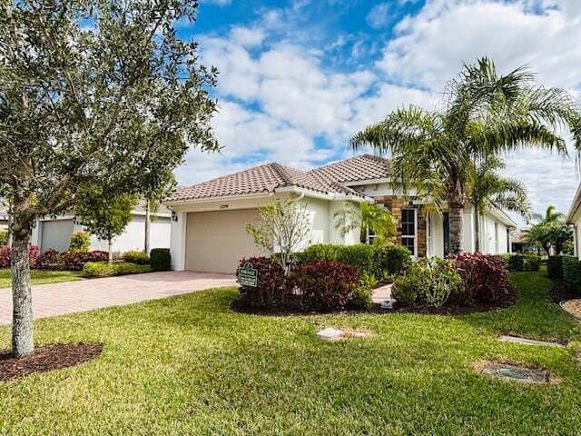 mediterranean / spanish-style home featuring a garage and a front lawn