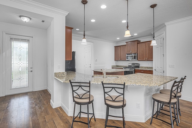 kitchen with light stone counters, hanging light fixtures, stainless steel appliances, and kitchen peninsula