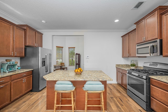 kitchen with stainless steel appliances, crown molding, a kitchen island, and a breakfast bar