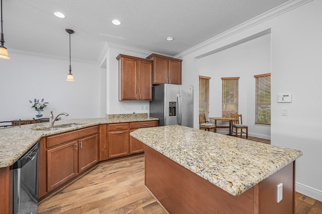 kitchen with sink, light stone counters, a kitchen island, pendant lighting, and stainless steel appliances