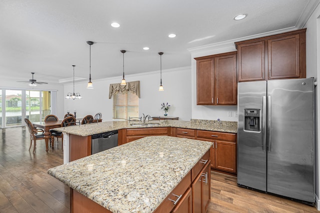 kitchen with stainless steel appliances, sink, a kitchen island with sink, and pendant lighting