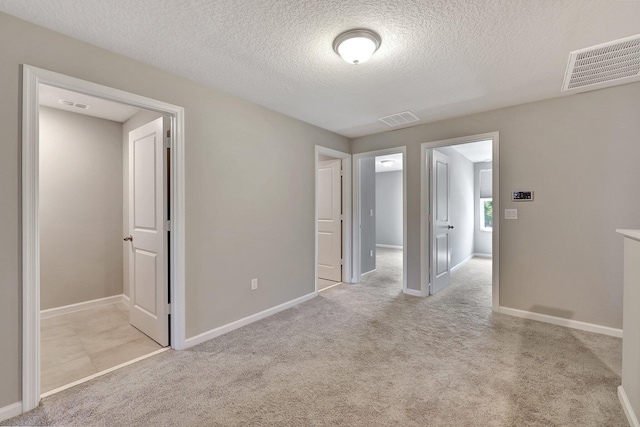 unfurnished bedroom featuring light carpet and a textured ceiling