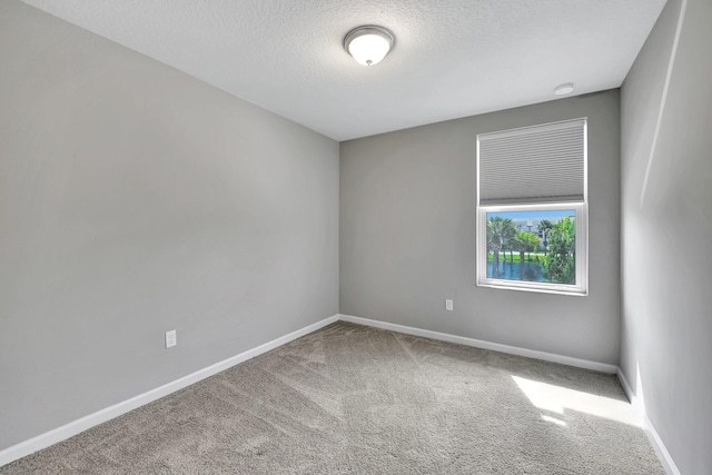 carpeted empty room featuring a textured ceiling