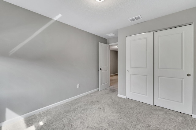 unfurnished bedroom featuring a closet, a textured ceiling, and light colored carpet