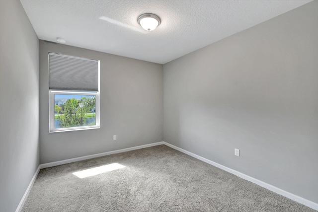 carpeted empty room featuring a textured ceiling