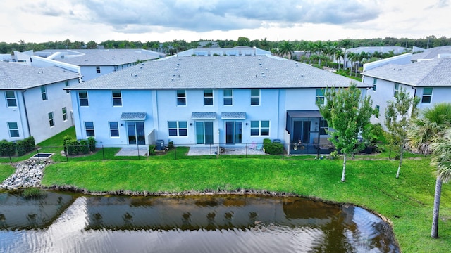 rear view of house with a patio, a water view, and a lawn