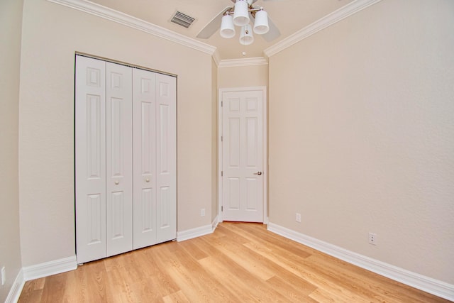 unfurnished bedroom featuring a closet, light hardwood / wood-style floors, crown molding, and ceiling fan