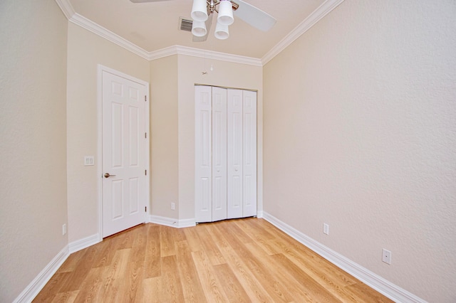 unfurnished bedroom with a closet, light hardwood / wood-style floors, crown molding, and ceiling fan