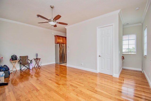 spare room with crown molding, light wood-type flooring, and ceiling fan