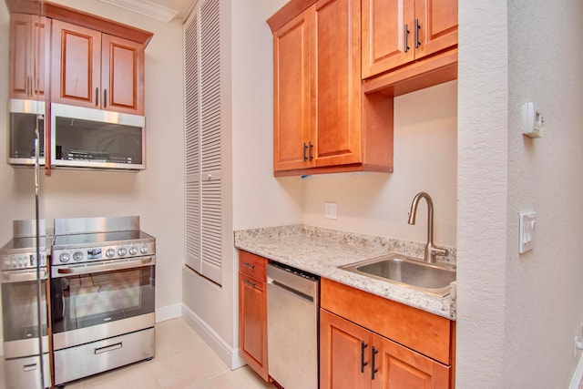 kitchen featuring appliances with stainless steel finishes, light stone counters, sink, and light tile patterned floors