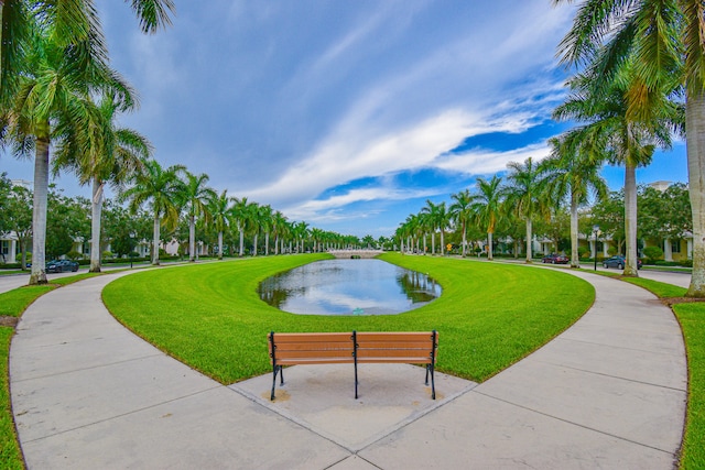 view of home's community with a water view and a lawn