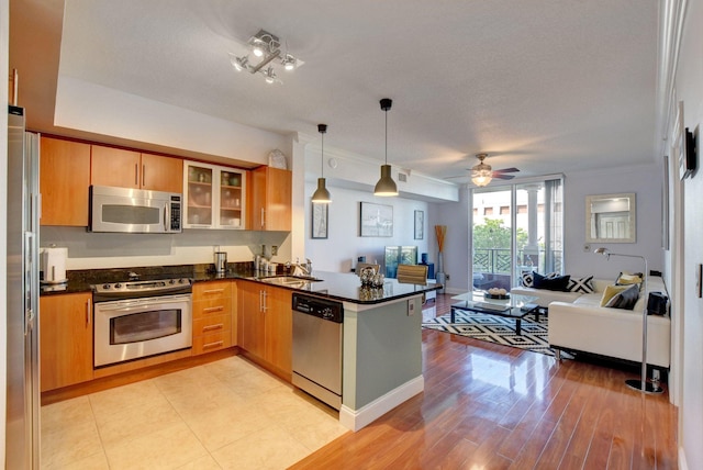 kitchen with ceiling fan, pendant lighting, kitchen peninsula, light hardwood / wood-style flooring, and appliances with stainless steel finishes