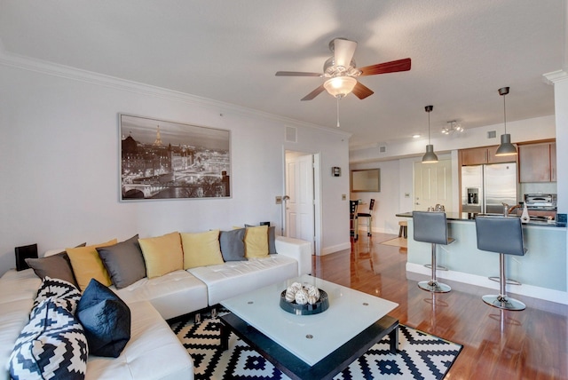 living room with wood-type flooring, ornamental molding, and ceiling fan