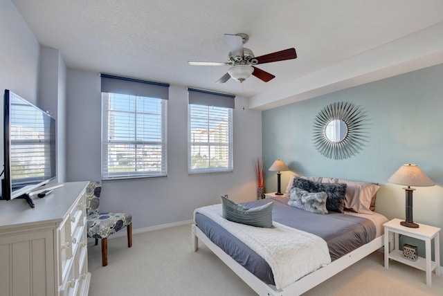 bedroom featuring light carpet, ceiling fan, and a textured ceiling