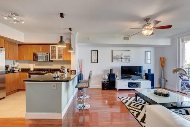 kitchen featuring light hardwood / wood-style floors, kitchen peninsula, a kitchen bar, and stainless steel appliances