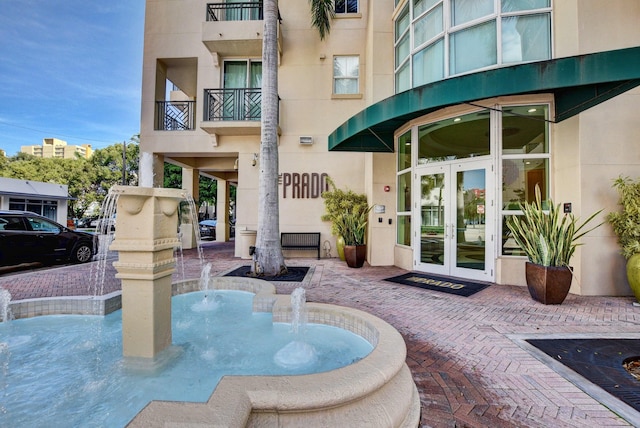 exterior space with pool water feature, a balcony, and french doors