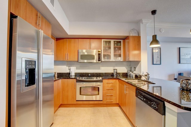 kitchen featuring pendant lighting, sink, kitchen peninsula, stainless steel appliances, and dark stone countertops