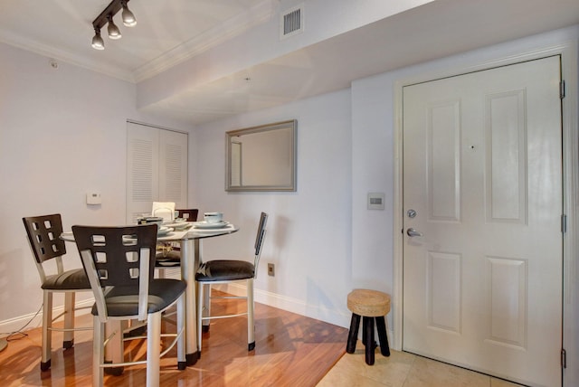 dining space featuring light hardwood / wood-style flooring, track lighting, and crown molding