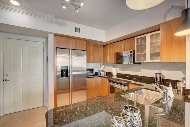 kitchen featuring dark stone counters, appliances with stainless steel finishes, light tile patterned floors, and sink