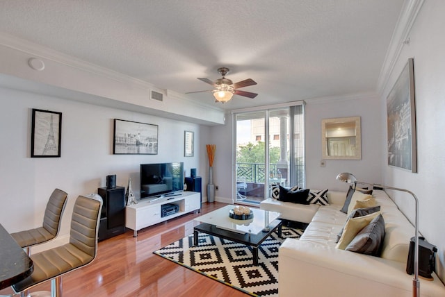 living room featuring ornamental molding, ceiling fan, a textured ceiling, and hardwood / wood-style floors