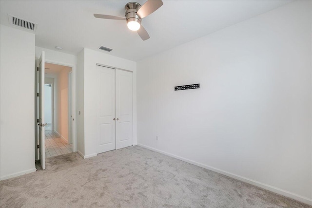 unfurnished bedroom featuring ceiling fan, light colored carpet, and a closet