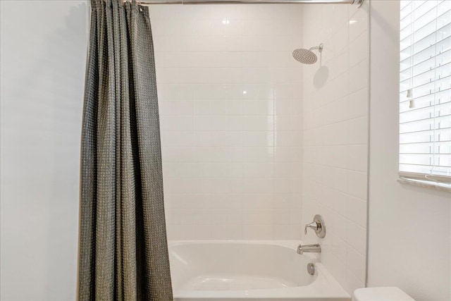 bathroom with shower / bath combination with curtain and toilet