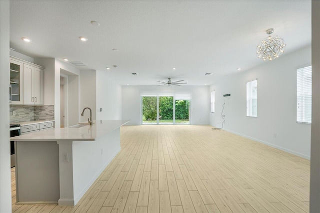 kitchen featuring a kitchen island with sink, white cabinetry, sink, and light hardwood / wood-style flooring