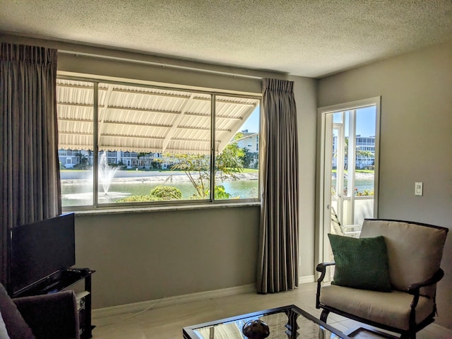 living area with a water view and a textured ceiling