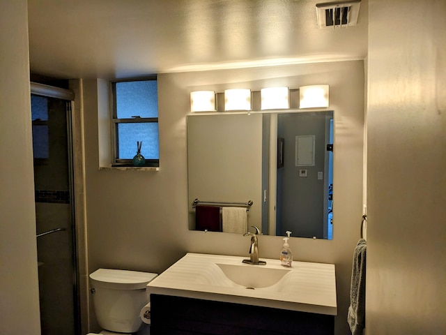 bathroom featuring toilet, a shower with shower door, and vanity