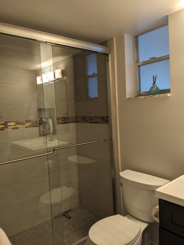 bathroom featuring toilet, an enclosed shower, and vanity