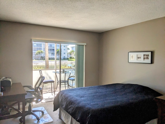 carpeted bedroom featuring a textured ceiling and access to exterior